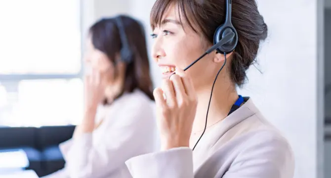 ヘッドセットを装着して笑顔で電話対応をする女性オペレーター