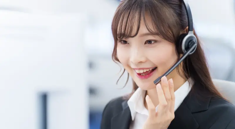 ヘッドセットを装着して笑顔で通話対応をする女性オペレーター