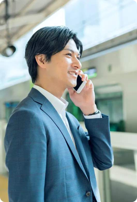 スマートフォンで電話をかけるスーツ姿の男性の画像